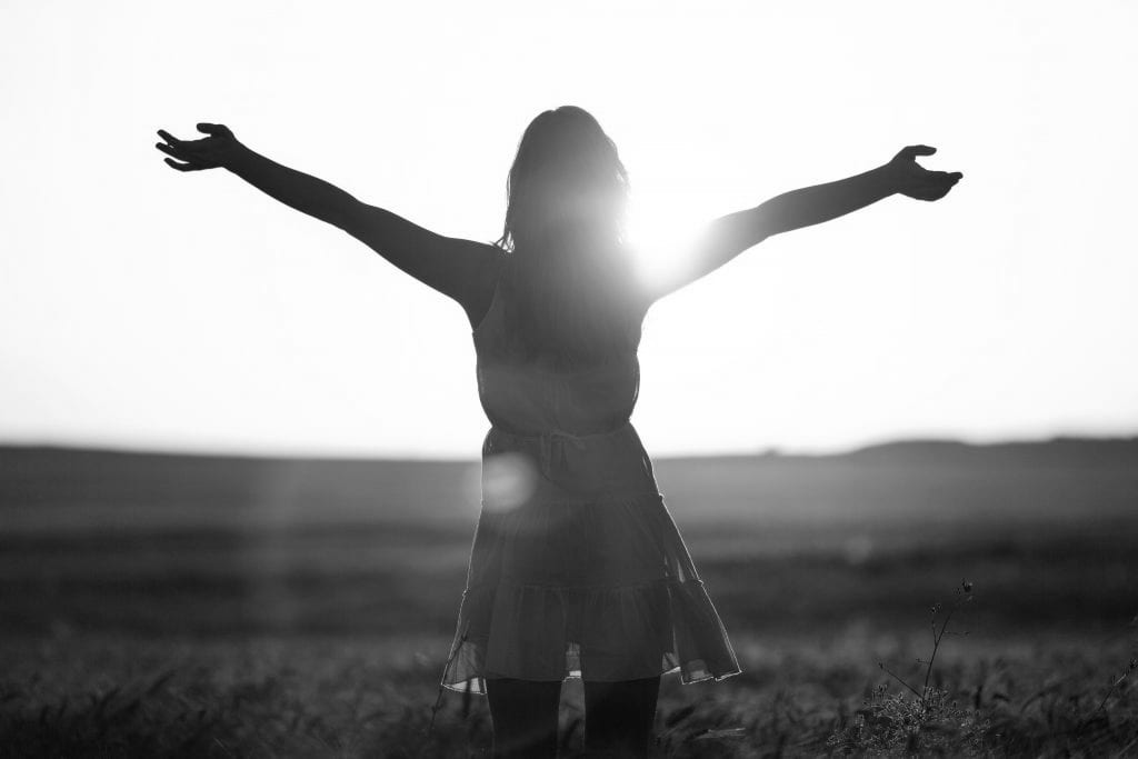 Woman standing in field with arms open Kinesiology services at Lighthouse Chiropractic & Integrative Health